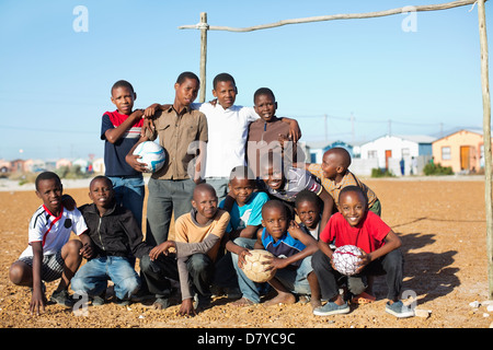 Boys holding soccer balls in dirt field Banque D'Images