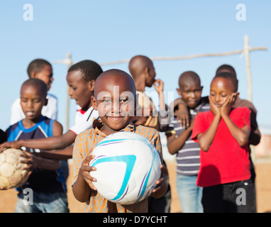 Boys holding soccer balls in dirt field Banque D'Images