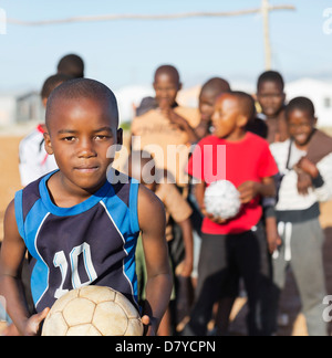 Boys holding soccer balls in dirt field Banque D'Images