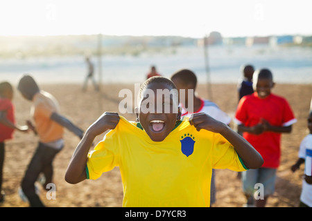 Boys playing soccer together in dirt field Banque D'Images