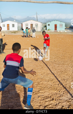 Boys playing soccer together in dirt field Banque D'Images