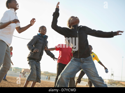 Boys playing soccer together in dirt field Banque D'Images