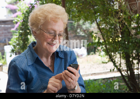 Older Hispanic woman using cell phone outdoors Banque D'Images