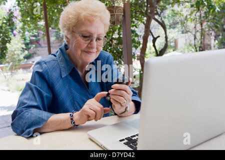 Older Hispanic woman using cell phone outdoors Banque D'Images