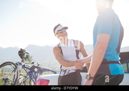 Les cyclistes shaking hands on rural road Banque D'Images