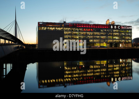 Illuminé, le siège de BBC Scotland sur Pacific Quay se reflète dans la rivière Clyde au coucher du soleil avec le pont Bell sur la gauche, Glasgow, Écosse, Royaume-Uni Banque D'Images