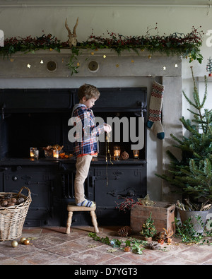 Boy decorating Christmas cheminée Banque D'Images