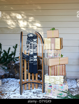 Foulard, un traîneau en bois et des cadeaux de Noël on snowy porch Banque D'Images