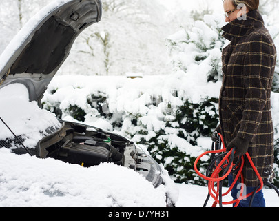 Femme au travail sur la neige en voiture en panne Banque D'Images