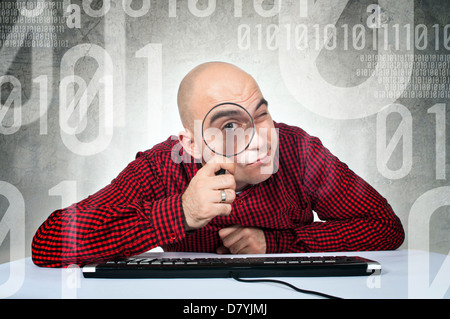 Recherche concept binaire. L'homme assis à la table d'ordinateur avec clavier holding loupe. Banque D'Images