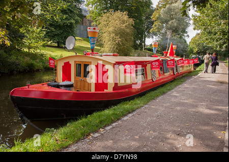 Bateau traditionnels colorés amarrés sur journée ensoleillée (floating boutique vendant des glaces) - scenic Leeds Liverpool Canal, Saltaire, England, UK. Banque D'Images