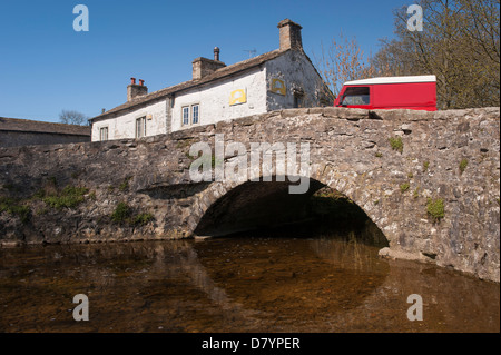 Land Rover Defender sur pierre historique pont à travée unique au-dessus Malham Beck dans le pittoresque village de Dales sur sunny day - Malham, North Yorkshire, England, UK Banque D'Images