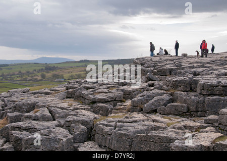 Personnes debout et marcher sur les lapiez, caractéristique naturelle spectaculaire en haut de Malham Cove - Malhamdale, Yorkshire, Angleterre, Royaume-Uni. Banque D'Images