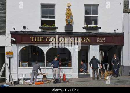 Les hommes de repeindre la façade de la Golden Lion Pub, dans la ville de Keswick, Parc National de Lake District, Cumbria, Angleterre, Royaume-Uni Banque D'Images