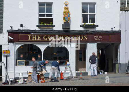 Les hommes de repeindre la façade de la Golden Lion Pub, dans la ville de Keswick, Parc National de Lake District, Cumbria, Angleterre, Royaume-Uni Banque D'Images