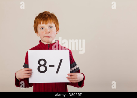 Caucasian boy holding card avec visage maladroit Banque D'Images