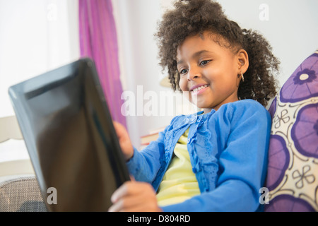 African American girl using tablet computer on sofa Banque D'Images