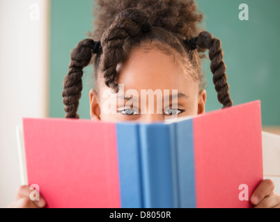 African American girl reading book in classroom Banque D'Images