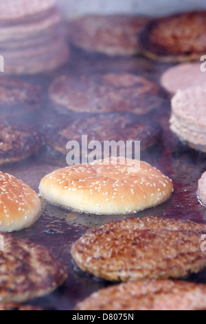 Hamburgers transformés crus et cuits sur une télévision commerciale grill à un événement en plein air Banque D'Images