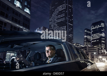 Caucasian businessman driving on city street Banque D'Images