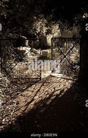 La lumière du soleil du soir casting son modèle ombre du portail en fer forgé en partie ouverte sur le chemin menant à Bosham Church Banque D'Images