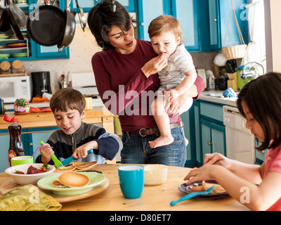 La mère et les enfants hispaniques ayant le petit déjeuner Banque D'Images