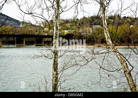 Ville de Harpers Ferry à partir de l'autre côté de la rivière Potomac en janvier. De jeunes arbres sans feuilles sycamore en premier plan ; pont de chemin de fer. Banque D'Images