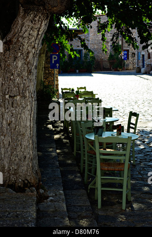 Le restaurant grec traditionnel, tables et chaises vides dans l'arbre d'ombre à journée ensoleillée. Banque D'Images