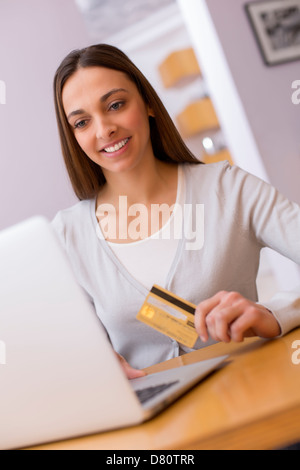 Femme tenant une carte de paiement et de shopping à partir du web sur l'ordinateur portable Banque D'Images