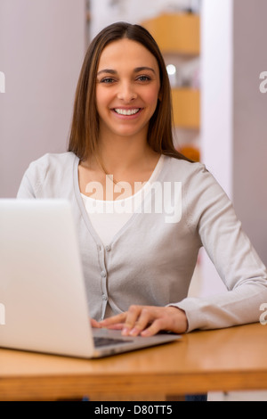 Portrait de femme simling derrière l'ordinateur Banque D'Images