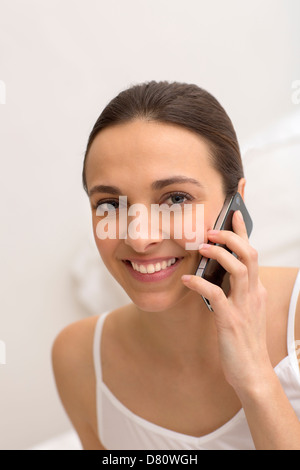 Jeune fille à l'aide de smart phone noir on bed Banque D'Images