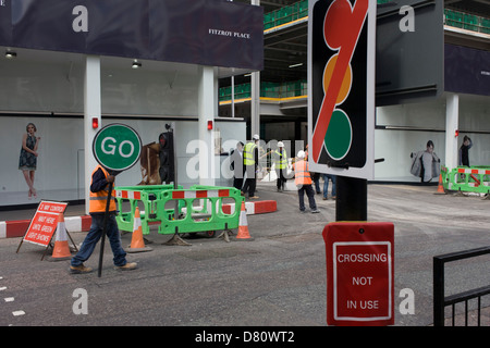 Les ouvriers de la construction d'un 'Stop' aller signer pour aider l'écoulement du trafic plus un hasard si 'non' des feux de croisement fermé à un signe. Retour à l'emplacement de l'édifice, l'homme marche retour à l'ouvert portes après l'arrêt de la circulation, un camion permettant de quitter le développement et re-inscrivez-vous sur le trafic local. Ce jeu de mots visuel est terminée avec une enseigne qui indique que les pilotes de feux de circulation normale sont inopérants. Banque D'Images