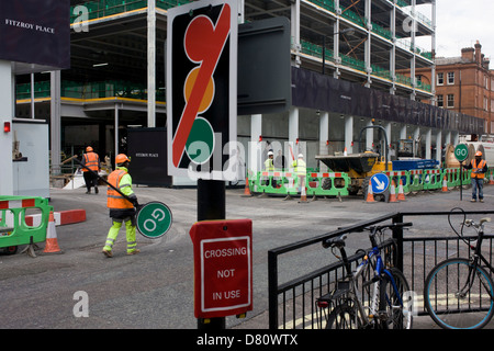 Les ouvriers de la construction d'un 'Stop' aller signer pour aider l'écoulement du trafic plus un hasard si 'non' des feux de croisement fermé à un signe. Retour à l'emplacement de l'édifice, l'homme marche retour à l'ouvert portes après l'arrêt de la circulation, un camion permettant de quitter le développement et re-inscrivez-vous sur le trafic local. Ce jeu de mots visuel est terminée avec une enseigne qui indique que les pilotes de feux de circulation normale sont inopérants. Banque D'Images