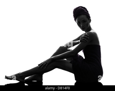 Une belle asiatique young woman sitting on floor serviette enroulée en silhouette studio isolé sur fond blanc Banque D'Images