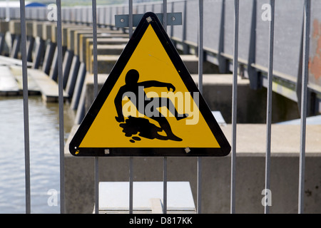 Un panneau d'avertissement indiquant une surface glissante près les vannes de la baie de Cardiff, Royaume-Uni. Banque D'Images