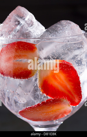 Cocktail gin tonic avec glace fraises gros plan macro sur noir Banque D'Images