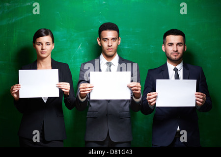 Partenaires d'affaires élégant avec des papiers vierges looking at camera sur fond vert Banque D'Images