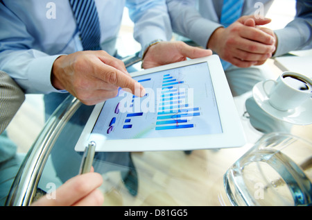 Les gens font des affaires modernes, graphiques et tableaux en démonstration sur l'écran d'un touchpad Banque D'Images