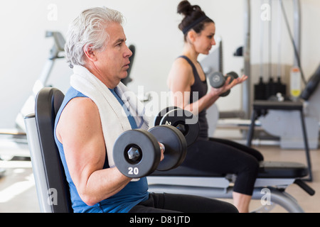 Older Hispanic man lifting weights in gym Banque D'Images