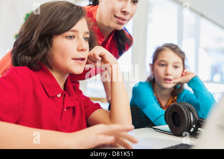 Enseignant et élèves using laptop in library Banque D'Images