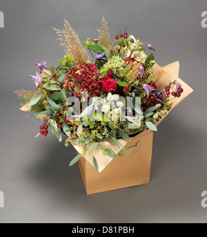 Gros Bouquet de fleurs roses et de fleurs de prairie notamment affiché dans une boîte en carton sur fond gris Banque D'Images
