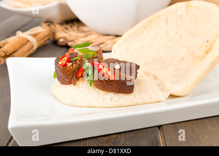 Hong Shao Rou - flan de porc braisé et caramélisées dans la sauce de soja à la badiane, la cannelle et le piment rouge à l'intérieur d'un petit pain à la vapeur. Banque D'Images