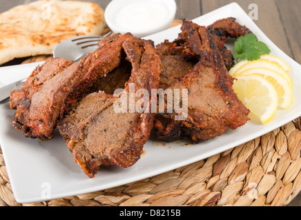 Côtelettes d'agneau tikka - South Asian côtelettes d'agneau grillées servies avec du pain naan, les quartiers de citron et raita. Banque D'Images