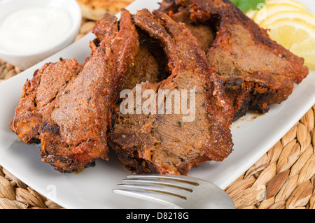 Côtelettes d'agneau tikka - South Asian côtelettes d'agneau grillées servies avec du pain naan, les quartiers de citron et raita. Banque D'Images