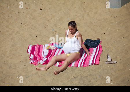 Femme enceinte beaucoup de soleil sur la plage de Bournemouth en mai Banque D'Images