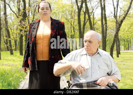 Closeup portrait d'un homme handicapé en fauteuil roulant d'être pris pour une promenade dans un parc boisé de sa femme Banque D'Images