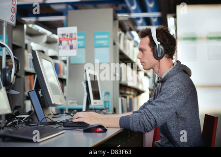 L'éducation, l'étudiant qui travaille à l'ordinateur dans la bibliothèque Banque D'Images