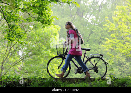 Un cycliste féminine en poussant son vélo le long de la Taff Trail sur une journée ensoleillée à Cardiff au Pays de Galles. Banque D'Images