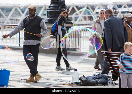 Les enfants bulles chasse faite par un artiste de rue sur la rive sud de Londres. Banque D'Images