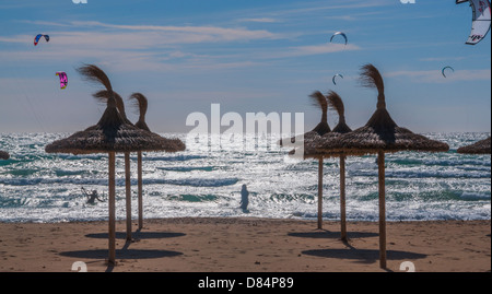 Surfers dans du vent fort et des parasols sur la plage. Banque D'Images